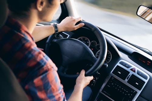 Free Close-up view of a man driving a modern car, showing dashboard and steering details. Stock Photo